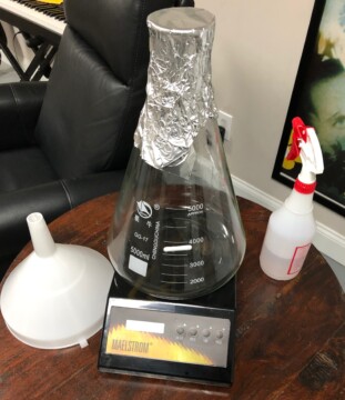 My stirplate set-up with a stirplate, flask, stirbar, foil cap, funnel, and sanitizer bottle Yeast Starter Process